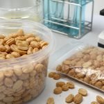 Maní tostado en envases sin marca junto a elementos de análisis de laboratorio