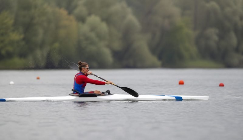 Deportista adulta compite en paracanotaje sobre una pista de aguas tranquilas
