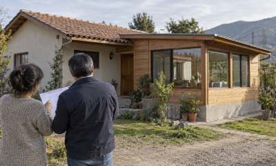 Propietaria y profesional revisan planos frente a una vivienda ampliada