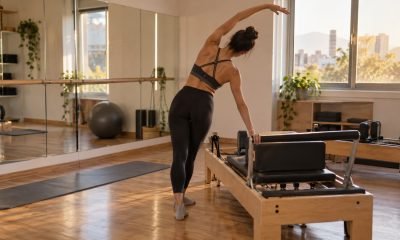 Joven practica movimiento corporal junto a una máquina Pilates Reformer en un estudio luminoso