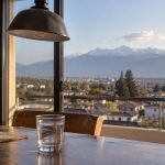 Vaso de agua con ondas suaves frente a una vista urbana y cordillerana de la zona central