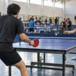 Jugadores adultos compiten en un encuentro de tenis de mesa en un gimnasio