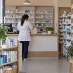 Profesional prepara un pedido en el mostrador de una farmacia de barrio