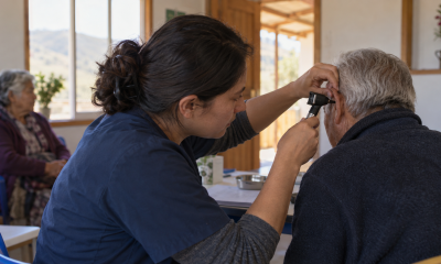 Profesional de salud realiza una evaluación auditiva a una persona mayor en un centro comunitario