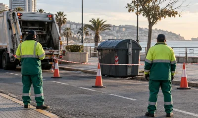 Recolectores de residuos observan un perímetro de seguridad junto a un contenedor en una imagen editorial referencial