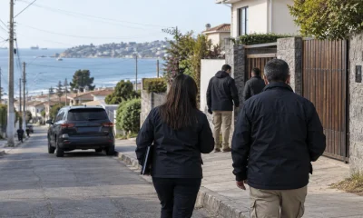 Equipo investigador se aproxima a una vivienda durante un procedimiento en una imagen editorial referencial