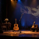 Escenario teatral con guitarras y micrófonos preparado para un concierto en una imagen editorial referencial