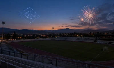 Representación editorial de las alternativas de drones y fuegos artificiales sobre un estadio vacío al anochecer
