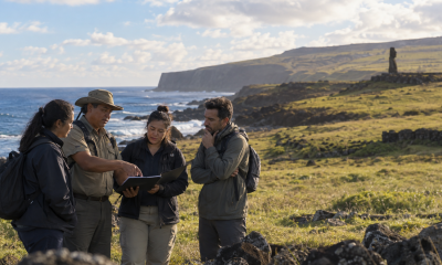 Guías turísticos revisan material de trabajo junto a la costa de Rapa Nui en una imagen editorial