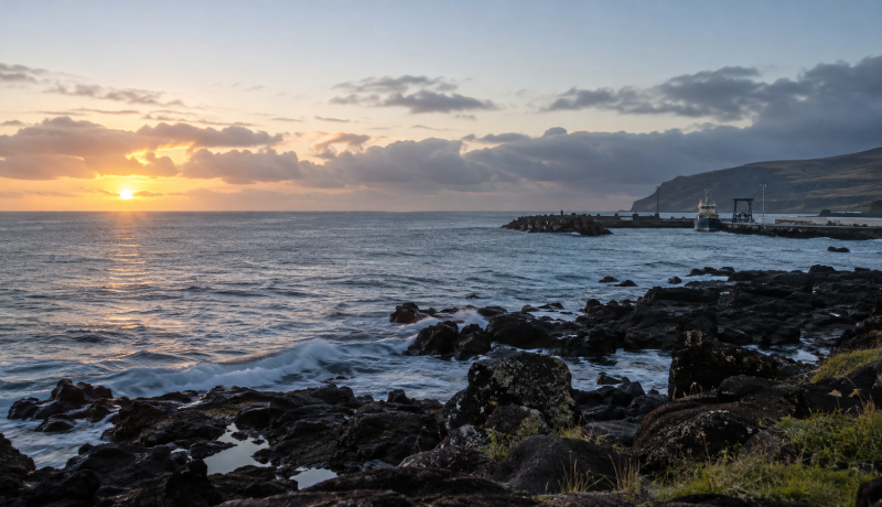 Vista costera referencial de Rapa Nui con una embarcación distante