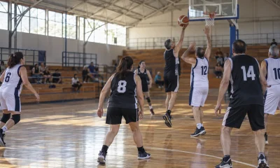 Personas adultas disputan un partido de básquetbol en un gimnasio comunitario
