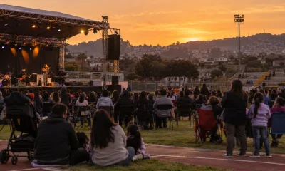Festival de música comunitario en un estadio municipal al atardecer