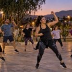 Vecinas y vecinos participan en una clase comunitaria de baile y ejercicio al anochecer