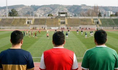 Tres hinchas con colores de clubes de la Región de Valparaíso observan una cancha antes de los partidos del fin de semana