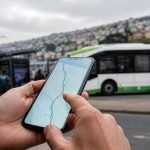 Persona consulta una ruta de transporte público en un teléfono frente a un bus en Valparaíso