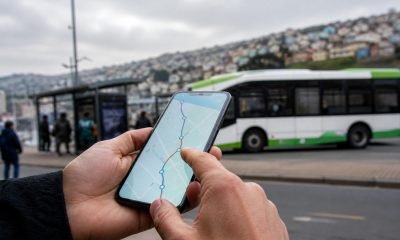 Persona consulta una ruta de transporte público en un teléfono frente a un bus en Valparaíso