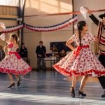 Parejas de estudiantes bailan cueca en un gimnasio escolar
