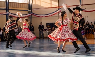 Parejas de estudiantes bailan cueca en un gimnasio escolar