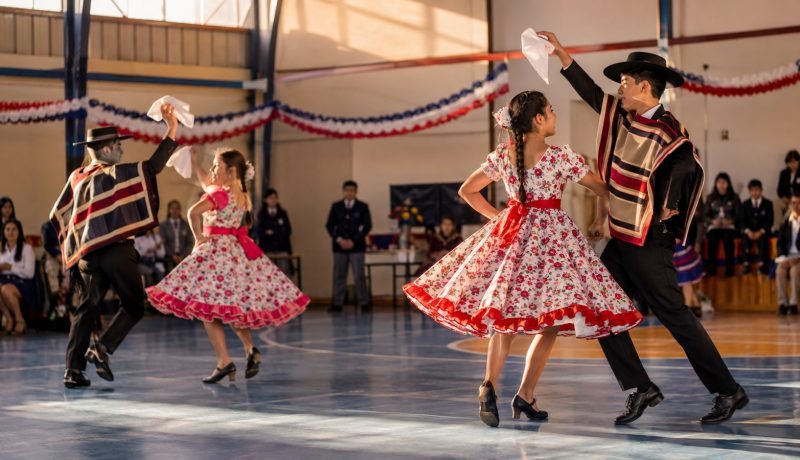 Parejas de estudiantes bailan cueca en un gimnasio escolar