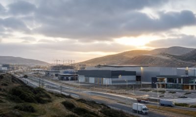 Parque industrial y logístico entre cerros bajo cielo nublado al amanecer