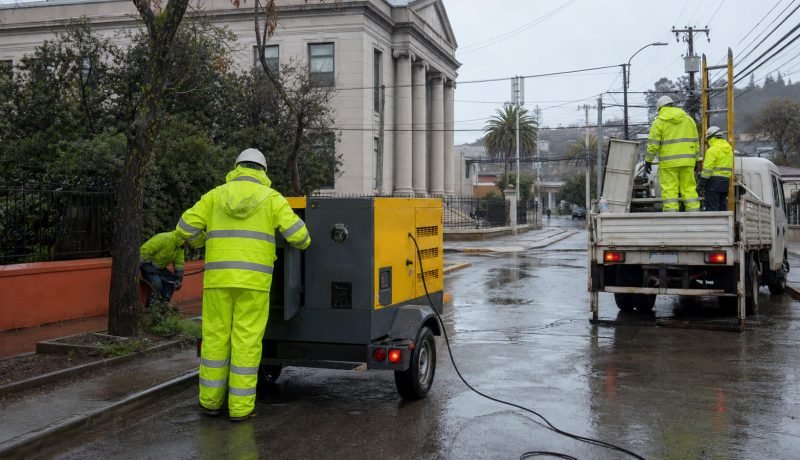Cuadrilla eléctrica y generador móvil en una calle mojada después del temporal