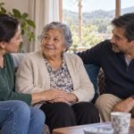 Persona mayor conversa acompañada por dos familiares en una sala de estar