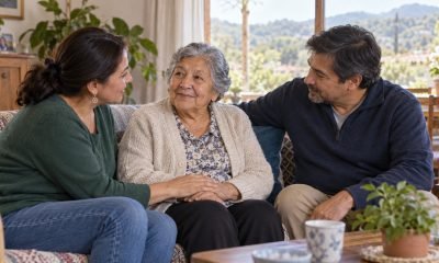 Persona mayor conversa acompañada por dos familiares en una sala de estar