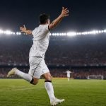 Futbolista de camiseta blanca celebra un gol en un estadio iluminado de noche