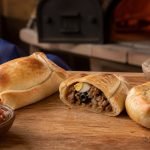 Empanadas chilenas de pino y pequén recién horneadas en una mesa de cocina