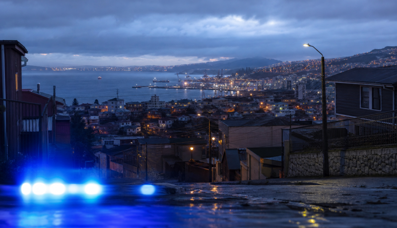 Vista urbana nocturna de la Región de Valparaíso con una luz de seguridad en primer plano