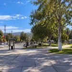Plaza arbolada de La Cruz, con senderos, bancos y una iglesia al fondo.