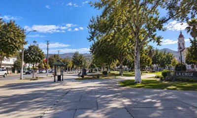 Plaza arbolada de La Cruz, con senderos, bancos y una iglesia al fondo.