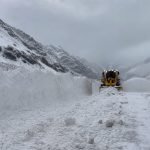 Máquina quitanieves despeja una ruta de alta montaña entre grandes bancos de nieve