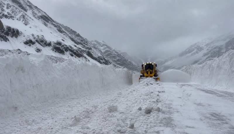 Máquina quitanieves despeja una ruta de alta montaña entre grandes bancos de nieve