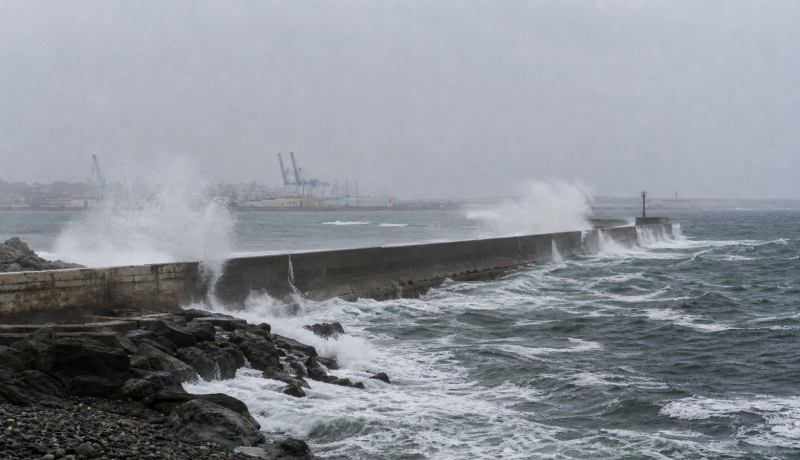 Molo portuario durante marejadas, imagen editorial referencial