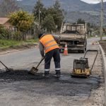 Trabajadores realizan bacheo en una calle comunal junto a una acera nueva