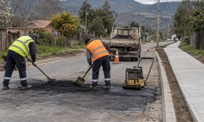 Trabajadores realizan bacheo en una calle comunal junto a una acera nueva