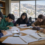Jóvenes estudian en una biblioteca con los cerros de Valparaíso al fondo