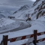 Ruta cordillerana cubierta de nieve con maquinaria de despeje y barrera de cierre