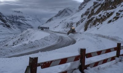 Ruta cordillerana cubierta de nieve con maquinaria de despeje y barrera de cierre