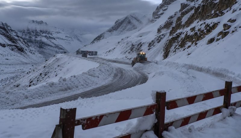 Ruta cordillerana cubierta de nieve con maquinaria de despeje y barrera de cierre