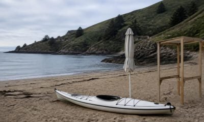 Kayak, quitasol plegado y estructura de madera en una playa de la costa central
