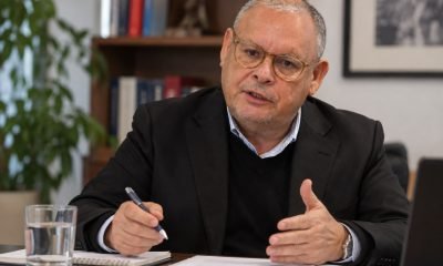Hombre con anteojos sentado ante documentos y un cuaderno en una oficina