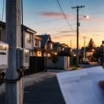 Medidores eléctricos en un barrio residencial chileno al atardecer mientras una persona revisa su cuenta de luz