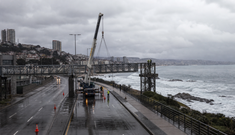 Imagen referencial del desmonte de una pasarela peatonal con grúa en una avenida costera tras un temporal