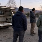 Camioneta con la parte trasera abierta junto a una comitiva en un sector rural