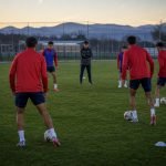 Futbolistas juveniles entrenan con balón en una cancha al atardecer