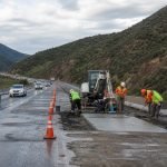 Trabajadores realizan obras de hormigón en una pista de autopista con tránsito habilitado al costado