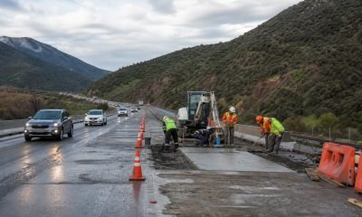 Trabajadores realizan obras de hormigón en una pista de autopista con tránsito habilitado al costado