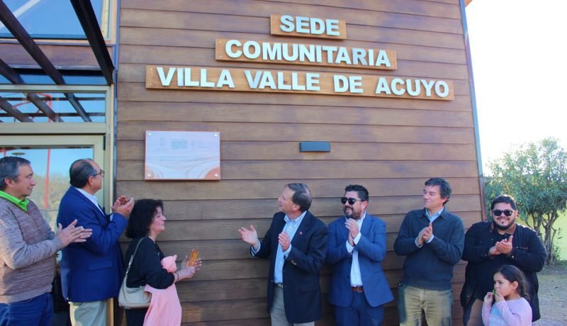 Personas frente a la sede comunitaria de Villa Valle de Acuyo, con el nombre del recinto visible en su fachada.